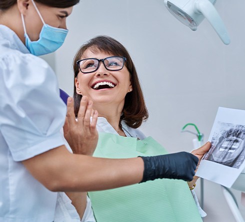 Dentist reviewing X-ray with smiling patient